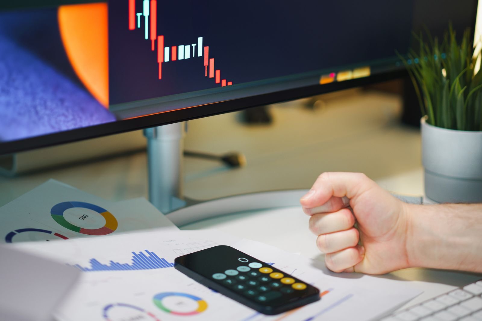 Risk management desk with position size calculator, printed charts and a phone